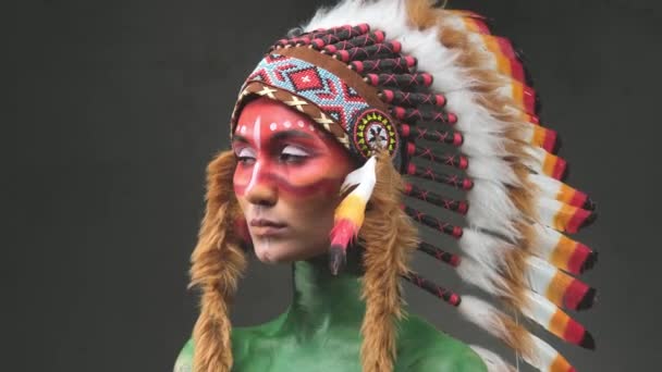 mooie vrouw droeg met tribal indiaanse hoofdtooi poseren in donkere achtergrond - Video
