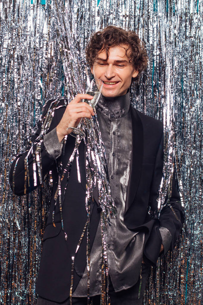 Holidays concept - happy tipsy man with a glass of champagne at christmas or new year party on a sparkle background. - Foto, Imagem