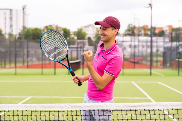 Male tennis player at the court looking happy - Photo, Image