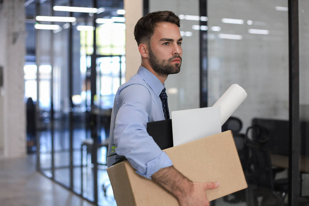 Sad dismissed worker is taking his office supplies with him from office - Фото, изображение