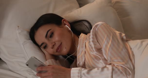 Krásná mladá žena poslech hudby při ležení v posteli - Záběry, video