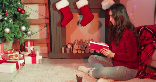 Nő könyvet olvas közel kandalló otthon karácsony este - Felvétel, videó