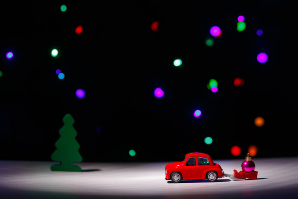 Irkutsk, Russland - 28. November 2020: Weihnachtsrotes Auto mit Schlitten und Weihnachtskugel an Heiligabend. Glückliches neues Jahr Kartenkonzept. - Foto, Bild