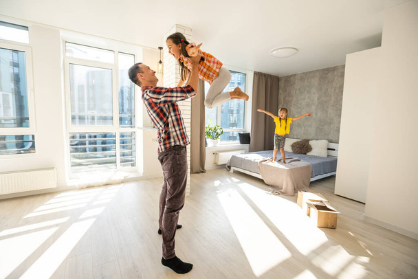 szczęśliwy ojciec i dwoje dzieci bawiących się i przytulających w domu na podłodze - Zdjęcie, obraz
