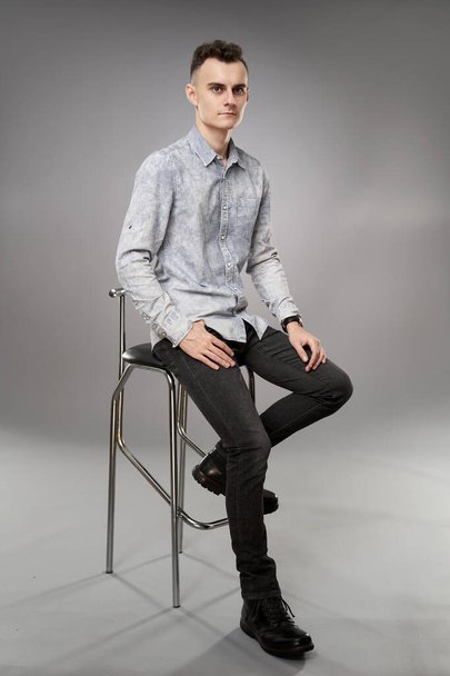 Full body shot of a young businessman sitting on a high chair - Фото, изображение