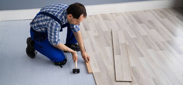 Hardwood Floor Renovation. Construction Worker Doing New Laminate Installation - Foto, afbeelding