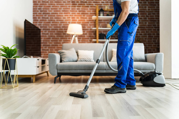 Man In Uniform Vacuuming House Floor. Cleaning Home - Φωτογραφία, εικόνα