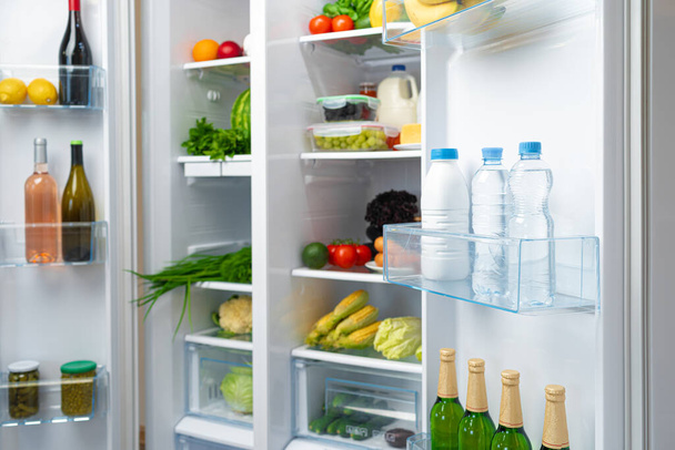 Open fridge full of fruits, vegetables and drinks - Фото, зображення