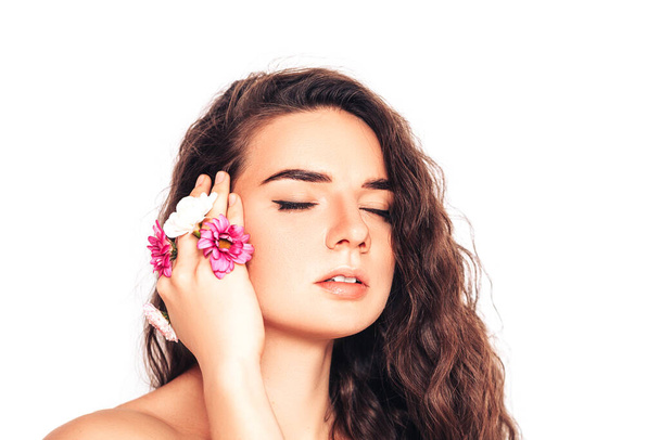 Young woman on a white background with flower in her hand near her face. - Foto, Bild