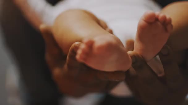 Aus nächster Nähe, Babyfüße. Vater-Sohn-Bindung. Afrikanischer Mann spielt mit kleinen Füßen seines Mulatten-Babys - Filmmaterial, Video
