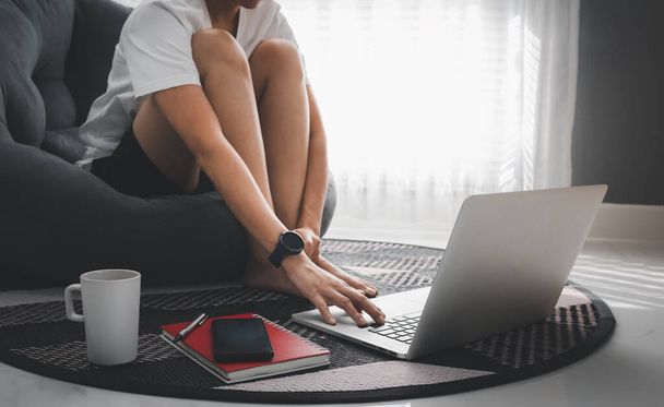 femme assis sur le sol avec ordinateur portable tout en travaillant à la maison pendant covid-19, concept de travail de la maison - Photo, image