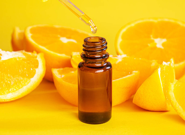 orange essential oil on a yellow background. Selective focus.nature - Φωτογραφία, εικόνα