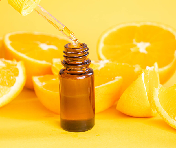 Ätherisches Orangenöl auf gelbem Hintergrund. Selektiver Fokus. - Foto, Bild