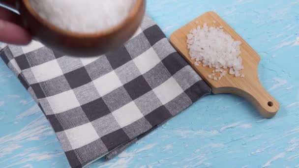 White sea salt in a natural wooden bowl blue background. Selective focus. copyspace - Footage, Video