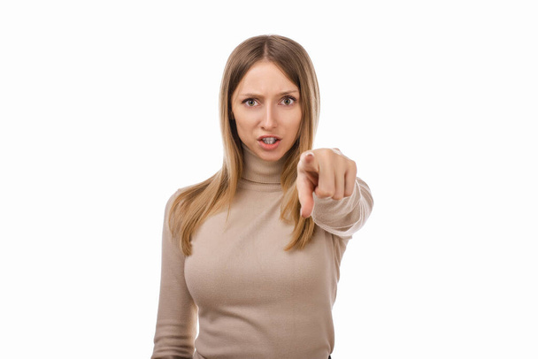 It's your fault. Displeased young blond woman in casual clothes is pointing finger at camera, angry and furious with you. Studio shot, white background - Photo, image
