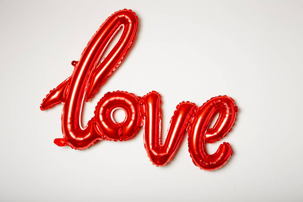Globo rojo con la palabra amor hecho de aluminio sobre fondo blanco. - Foto, imagen