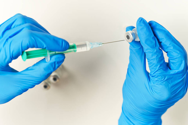 les mains du médecin injectant une aiguille de seringue dans un petit flacon avec un vaccin ou un médicament assignent le virus ou la grippe. - Photo, image