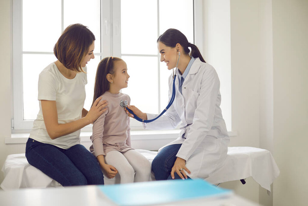 Friendly doctor listening to little patients breath or heartbeat during medical checkup - Photo, Image