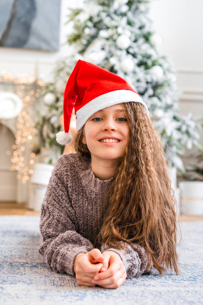 Мила дівчинка посміхається і дивиться на камеру в яскравій студії з різдвяними прикрасами - Фото, зображення
