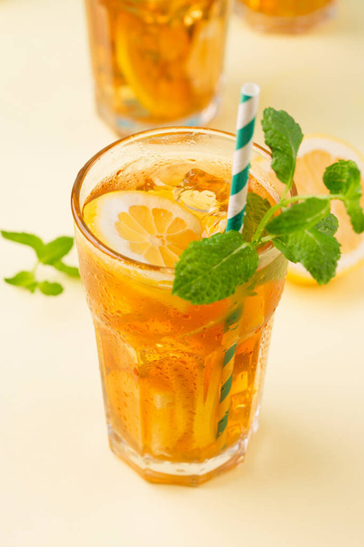 Tradiční domácí ledový čaj s citrónem, mátou a ledem ve vysokých sklenicích. Letní studený nápoj na žlutém pozadí. Zdravé letní jídlo koncept. Selektivní zaměření, kopírovací prostor.  - Fotografie, Obrázek