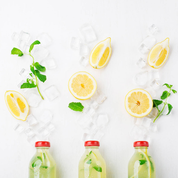 Fresh homemade summer  lemonade or mojito cocktail with lemon and mint. Cold refreshing drink or beverage with ice on white background. Top view, copy space. - Photo, Image