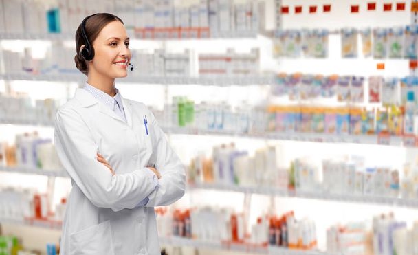 улыбающаяся женщина-врач с наушниками в аптеке - Фото, изображение