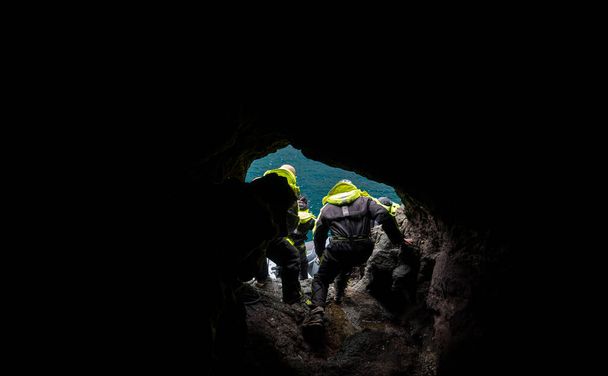 Persone irriconoscibili che saltano dalla grotta alla barca a motore - Foto, immagini