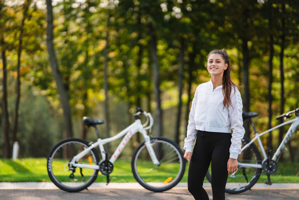 Mooi meisje poserend op een witte fiets. Wandelen in de natuur. - Foto, afbeelding