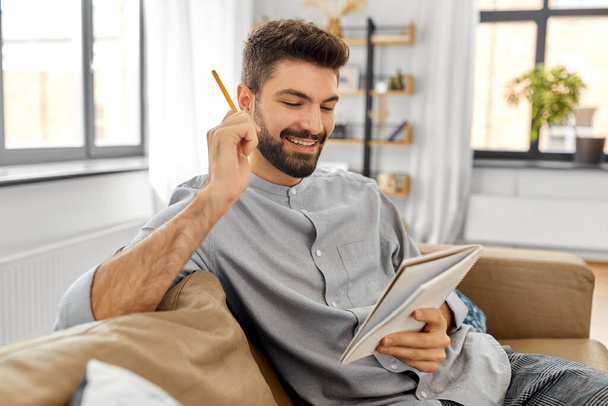 smiling man with to notebook and pencil at home - Photo, image