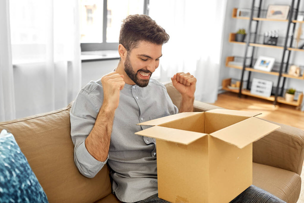 happy smiling man with open parcel box at home - Foto, Bild