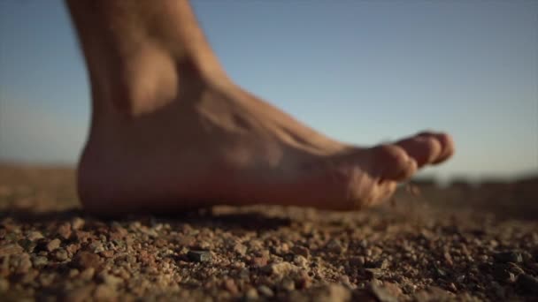 Gros plan du pied nu d'un homme marchant sur une terre désertique sèche, au ralenti - Séquence, vidéo