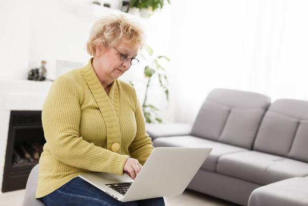 家庭でノートパソコンを使う幸せな高齢女性は - 写真・画像