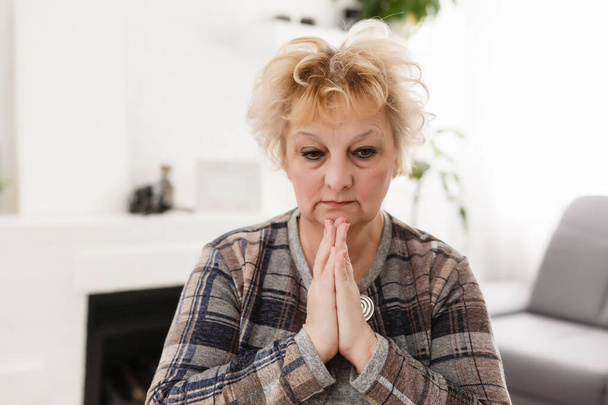İnançlı, dindar, orta yaşlı bir kadın umut dolu bir inançla dua ediyor. Sabahları evde el ele tutuşup dua eden olgun, inançlı bir Hıristiyan kadın dua ediyor. - Fotoğraf, Görsel