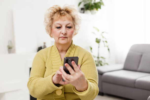 Ideges idős nő, aki érintőképernyős mobilt használ selfie készítésére vagy videohívásra - Fotó, kép
