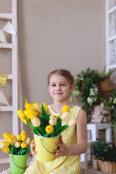 Linda chica en vestido amarillo con manojo de tulipanes amarillos.El día internacional de las mujeres   - Foto, imagen