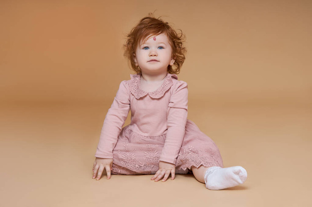 Portrait of a little red-haired girl with curly hair. A large mole on the child forehead - Фото, изображение