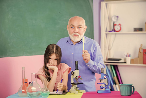 Where little things mean a lot. use magnifying glass. mature teacher of biology. Pupil girl in school lab. small girl with man tutor study chemistry. science classroom. Microscopy. Laboratory tools - Fotoğraf, Görsel