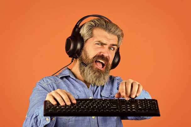 Superior performance. Online gaming. Modern leisure. Run any modern game. Graphics settings pushed to limit. Play computer games. Man bearded hipster gamer headphones and keyboard. Gaming addiction - Photo, image