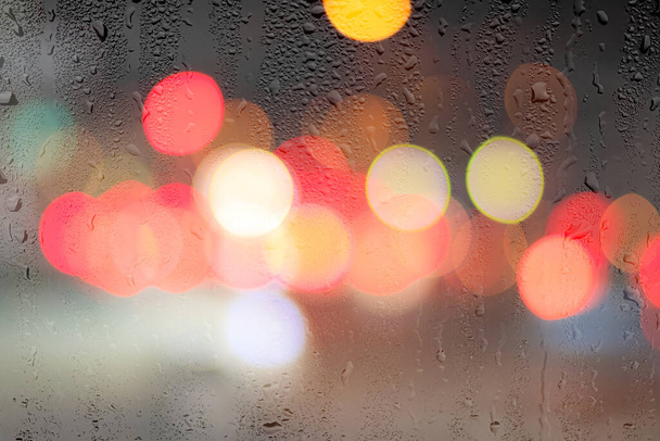 Gece lambaları ve araba farları yağmurlu camlarda. Yağmur ve kötü yağışlı hava kavramı. - Fotoğraf, Görsel