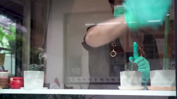 Biznes ponownie otwarty Kobieta kelner nosić maskę ręce czyszcząc szklane okno w restauracji, przygotowuje kawiarnię na otwarcie, sprzątanie przestrzeni roboczej - Materiał filmowy, wideo