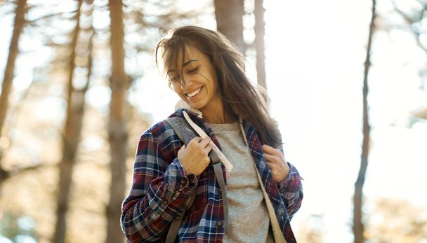 beweging portret optimistisch glimlachende vrouw in het bos met zonlicht op de achtergrond. - Foto, afbeelding