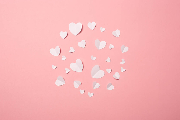 Witte papieren hartjes op een roze achtergrond. Samenstelling van Valentijnsdag. Een spandoek. Vlakke lay, bovenaanzicht. - Foto, afbeelding