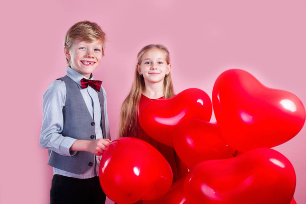 Valentines day. Children with red heart balloons on a pink background - Φωτογραφία, εικόνα