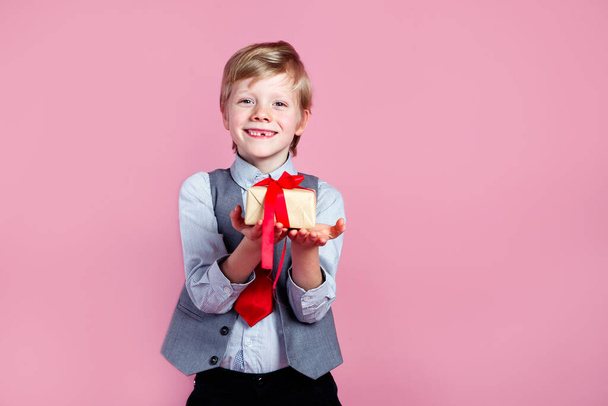 Valentines day. Charming little boy with gift box on pink studio background - Photo, Image