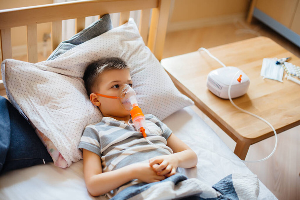 A young boy is given an inhalation during a lung disease. Medicine and care - Foto, Bild