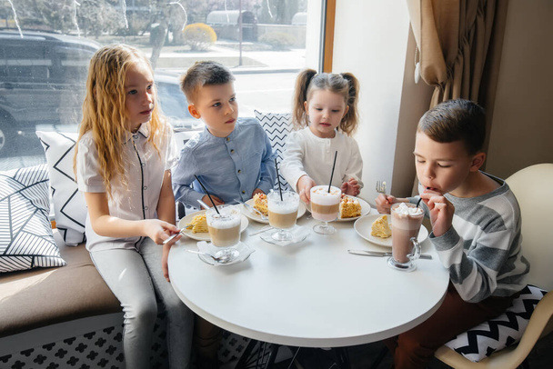 A large friendly company of children celebrate the holiday in a cafe with a delicious dessert. The day of the birth - Foto, imagen
