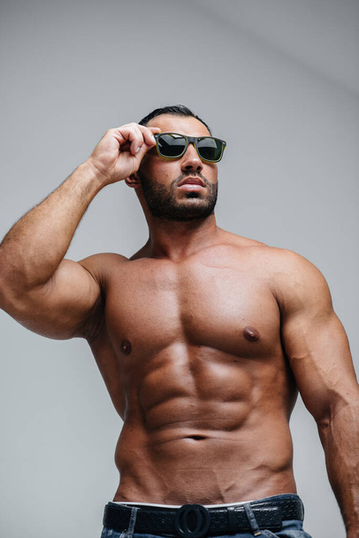 A sexy athlete with a naked torso is wearing glasses. Rest, healthy lifestyle - Фото, изображение