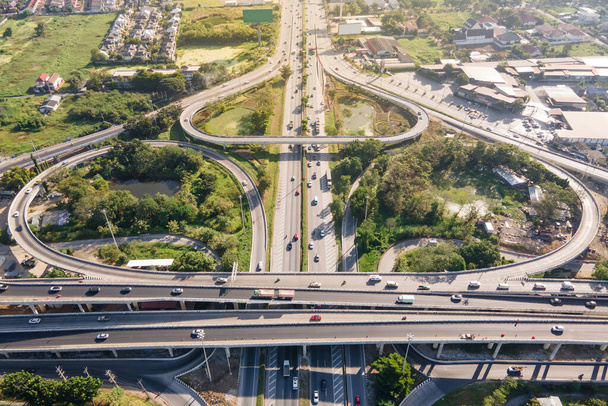 Luftaufnahme eines Verkehrsknotenpunktes oder Autobahnkreuzes mit stark befahrenem Stadtverkehr, der auf der Straße beschleunigt. Knotenpunkt-Transportnetz per Drohne. - Foto, Bild