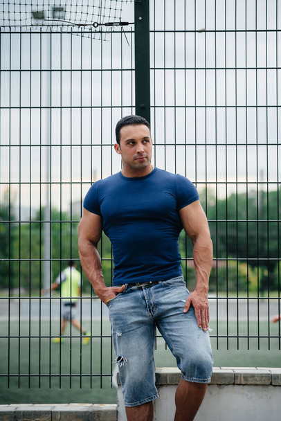 Sports guy stands near the sports field. Bodybuilding - Foto, afbeelding
