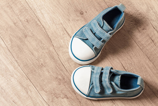 Cute baby blue sneakers on a wooden floor - Fotó, kép